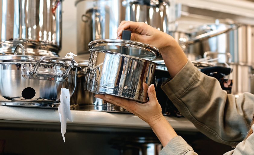 Young happy woman buying new cooking pot in the supermarket. Copy space.