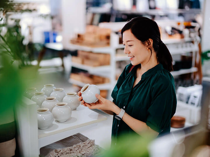 Asian adult female looking at a spherical planting pot in a store