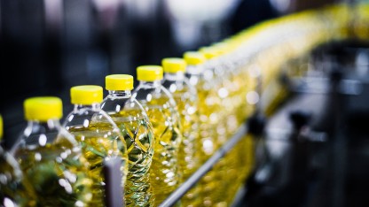 Bottles of oil moving along a conveyor belt, emphasizing the significance of food contact testing for packaging materials