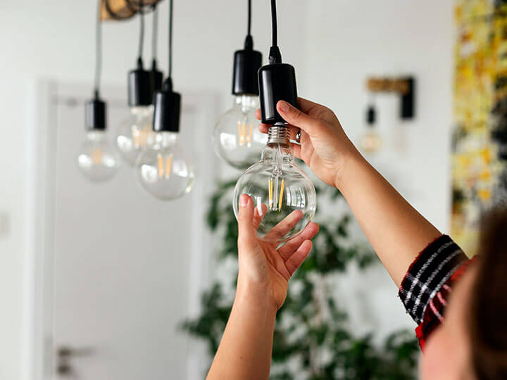 Close-up view of a Caucasian female changing a light bulb to an LED bulb