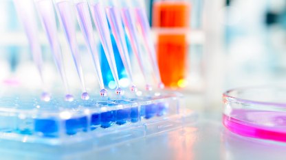 A lab scene with test tubes and a glass vial, representing biotechnology's role in enhancing quality in beauty products
