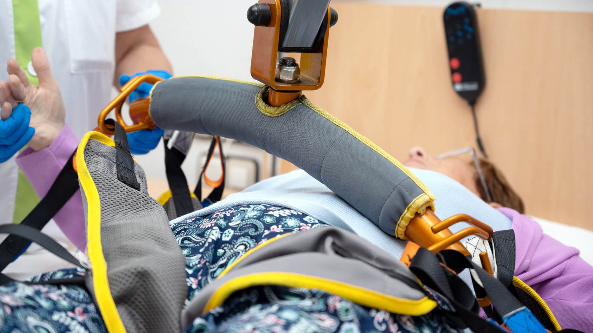A care staff using a power assist to lifts a patient at nursing home. High quality photo 